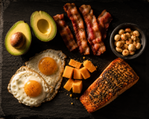 A traditional Mediterranean diet food spread with grilled fish, Greek salad, hummus, olives, olive oil, and whole grain pita on a rustic wooden table