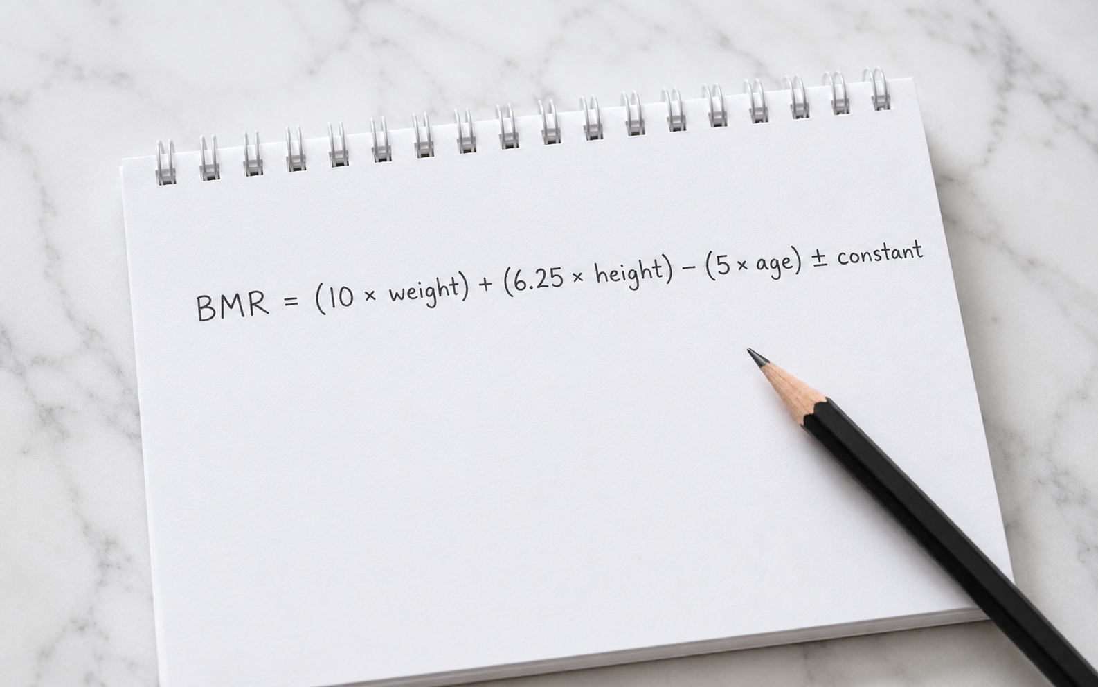 Handwritten Mifflin-St Jeor BMR formula on a notepad — the first step in calculating your calorie deficit